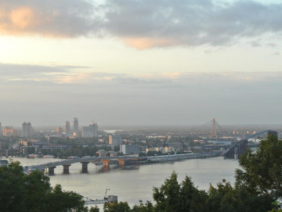 Vista de uma cidade ao entardecer, com rio e pontes ao fundo
