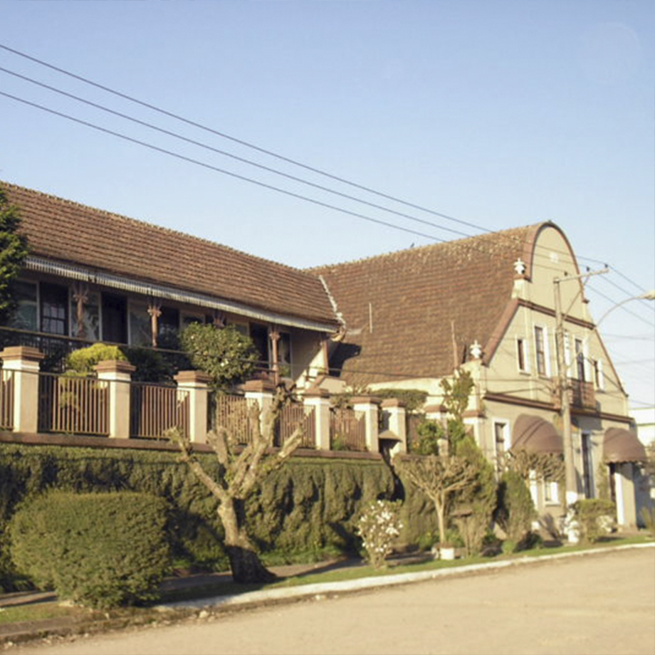 Edifício de dois andares com telhado inclinado e jardim bem cuidado.